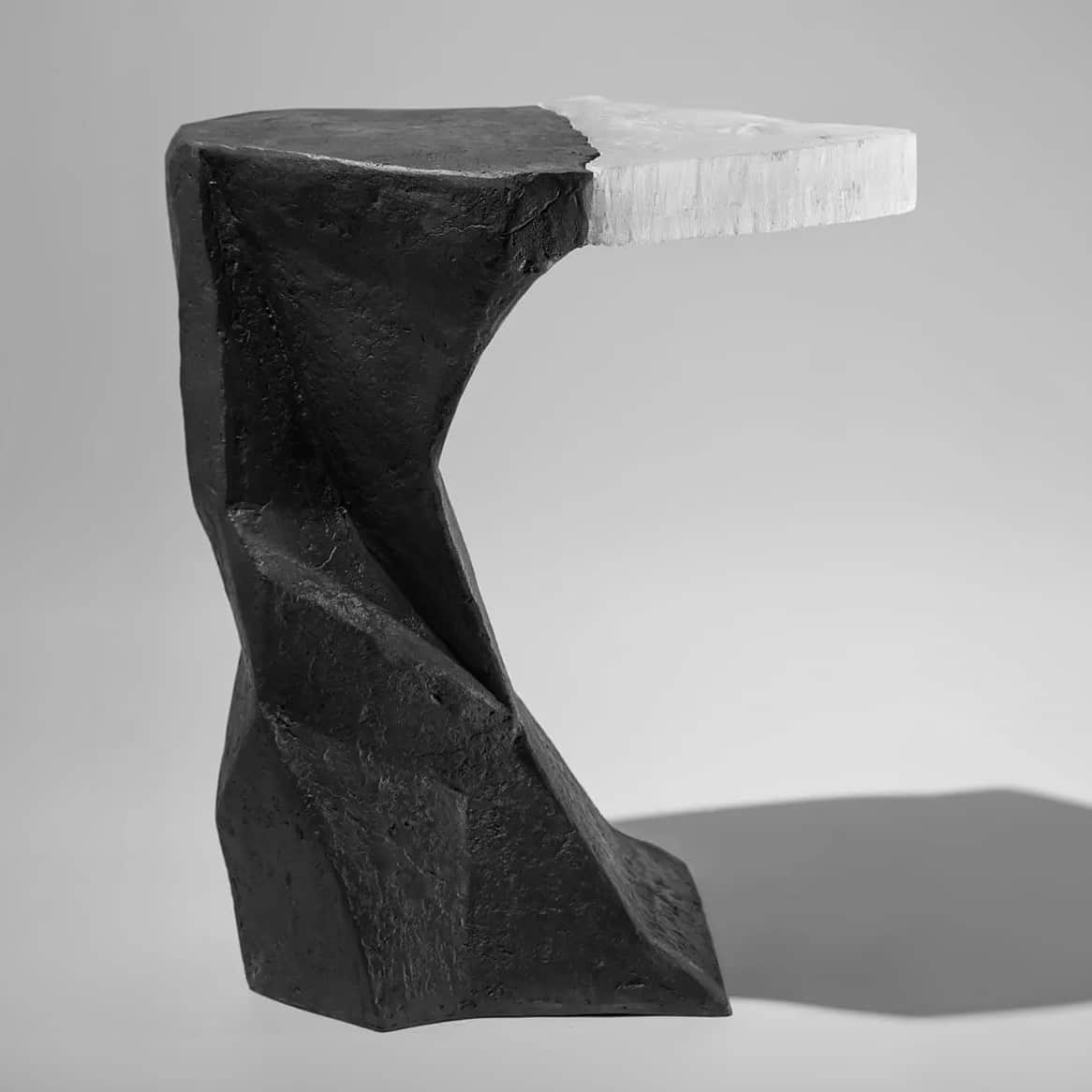 A sculptural accent table featuring an abstract, angular base crafted from a dark, rough-textured ma… — 3D model