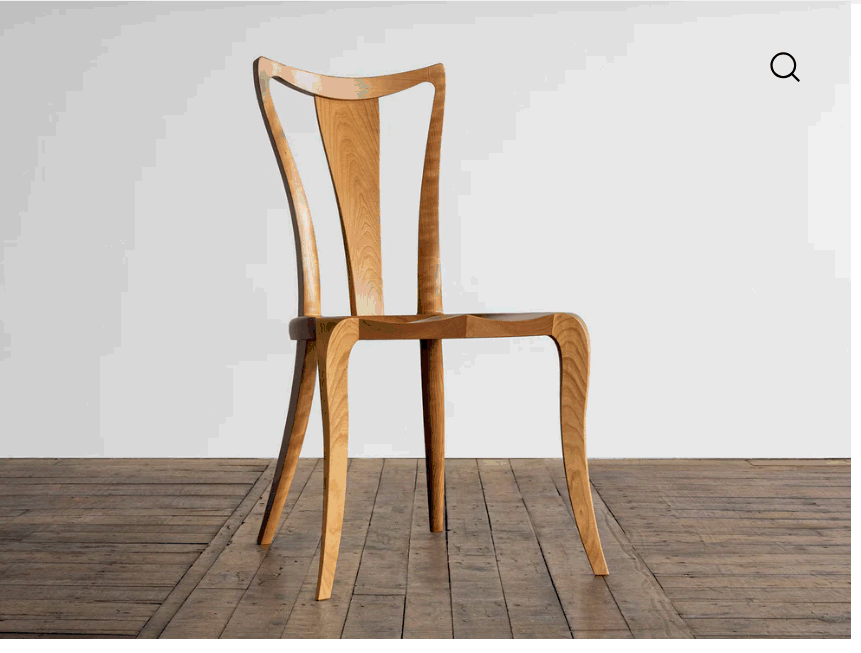 A modern, armless side chair crafted from light-toned wood, featuring a distinctively curved backres… — 3D model
