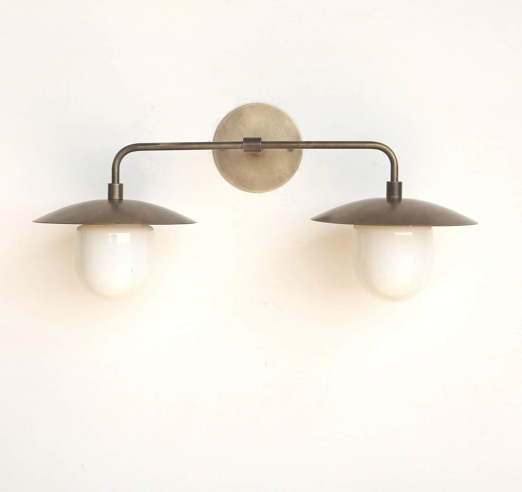A double arm wall sconce featuring an aged brass or bronze finish. It consists of a circular backpla… — 3D model