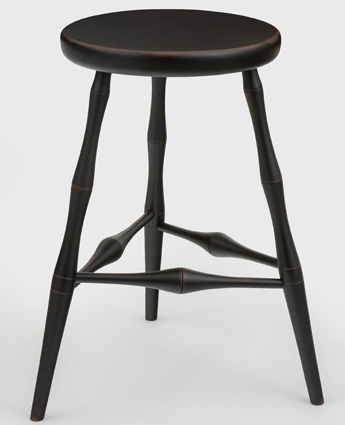 A dark, likely black-painted, wooden stool with a round seat and three splayed, turned legs. The leg… — 3D model