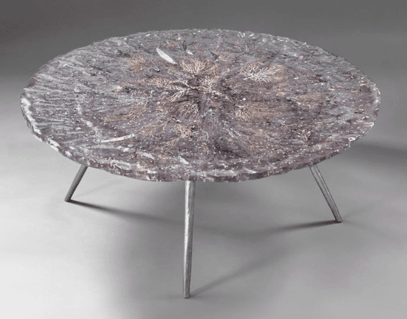 A circular coffee table with a dark, textured top featuring embedded organic or decorative elements.… — 3D model