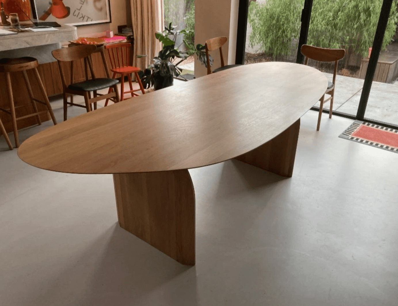 An oval coffee table with a light wood finish and two angled pedestal bases. The table has a minimal… — free BLEND 3D model