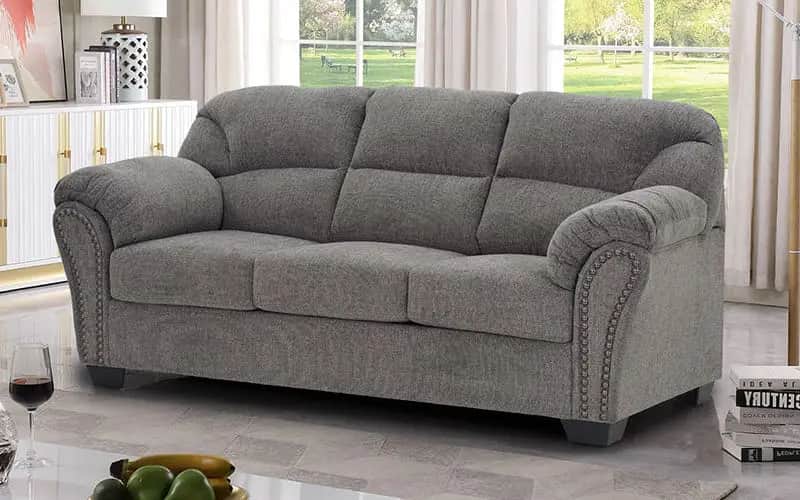 A grey upholstered three-seater sofa featuring rolled arms with nailhead trim and individual seat an… — free GLTF 3D model