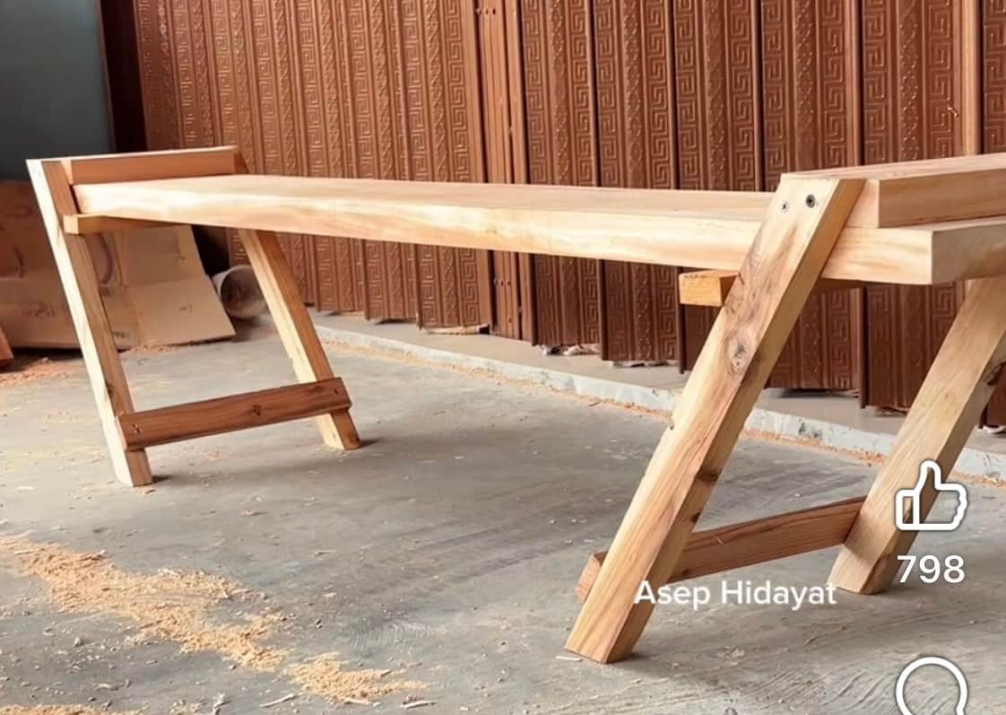 A minimalist slatted wooden bench with angled A-frame style legs, featuring light natural wood and v… — 3D model