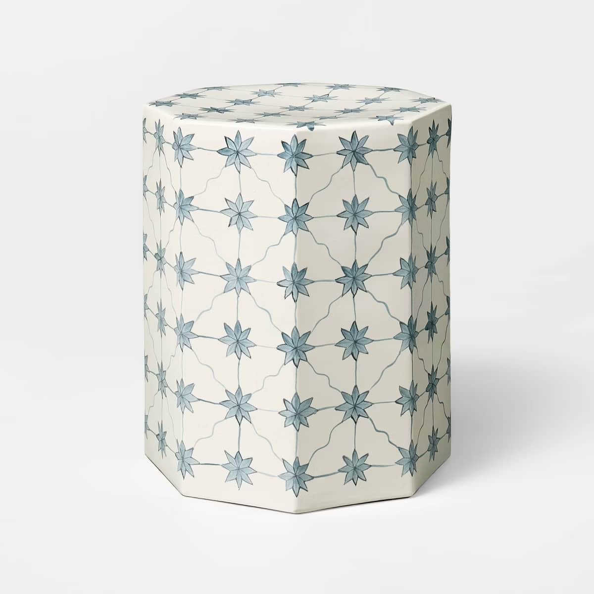 A hexagonal side table with a cream-colored base and a decorative pattern of light blue star-shaped… — 3D model