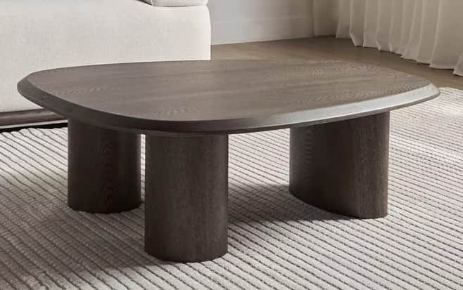 A dark stained wood coffee table featuring a rounded rectangular top supported by three thick cylind… — 3D model