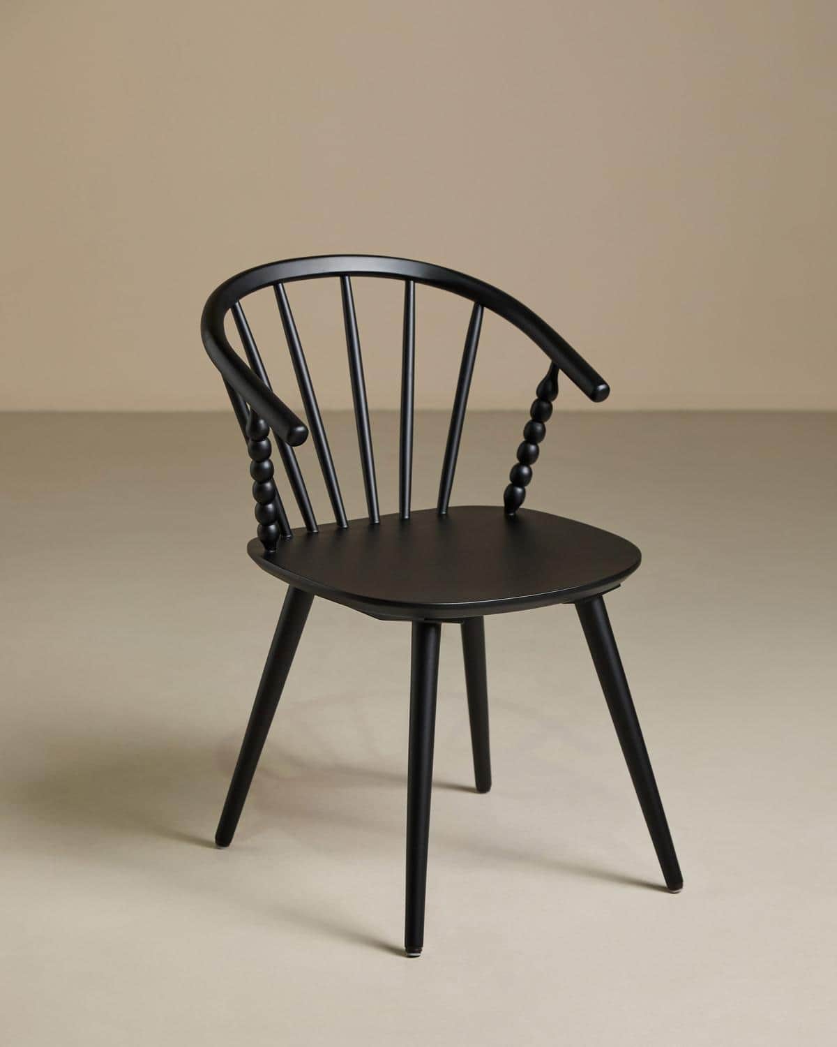 A contemporary armchair featuring an all-black finish. It has a curved spindle backrest that flows i… — 3D model