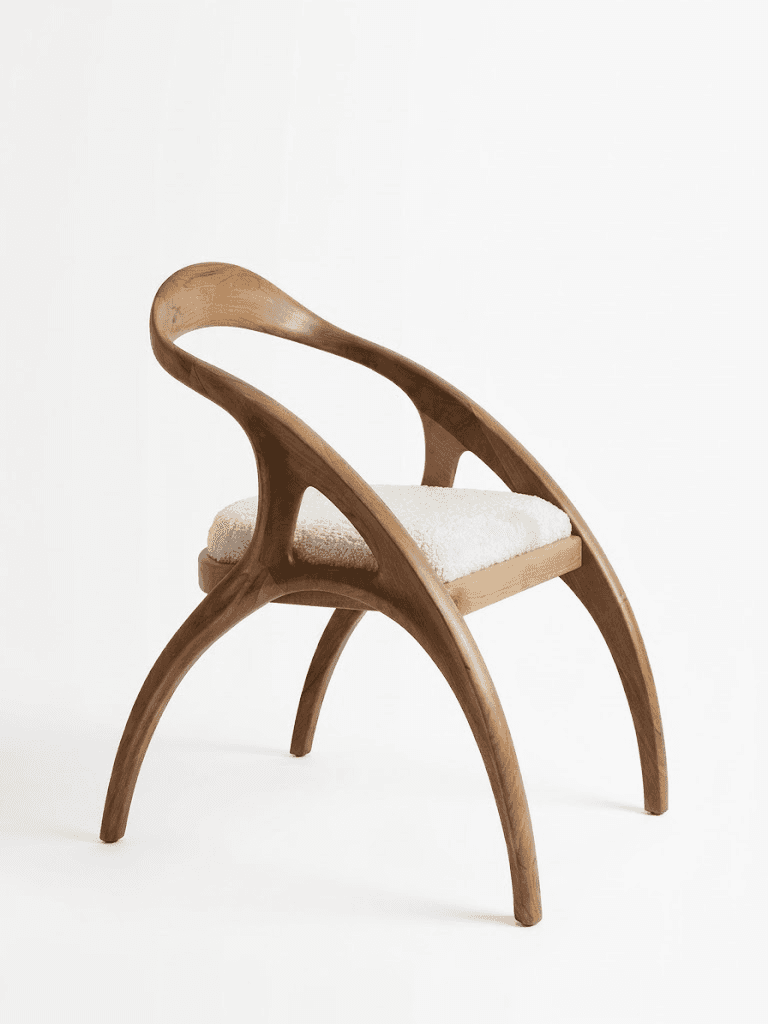 A sculptural armchair featuring a curved solid wood frame and a plush, light-colored upholstered sea… — 3D model