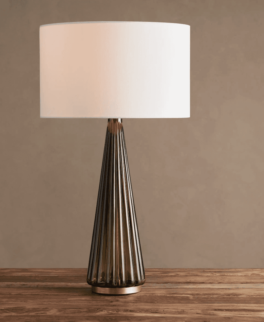 A modern table lamp featuring a conical, fluted base made of smoked glass, accented with brass eleme… — 3D model