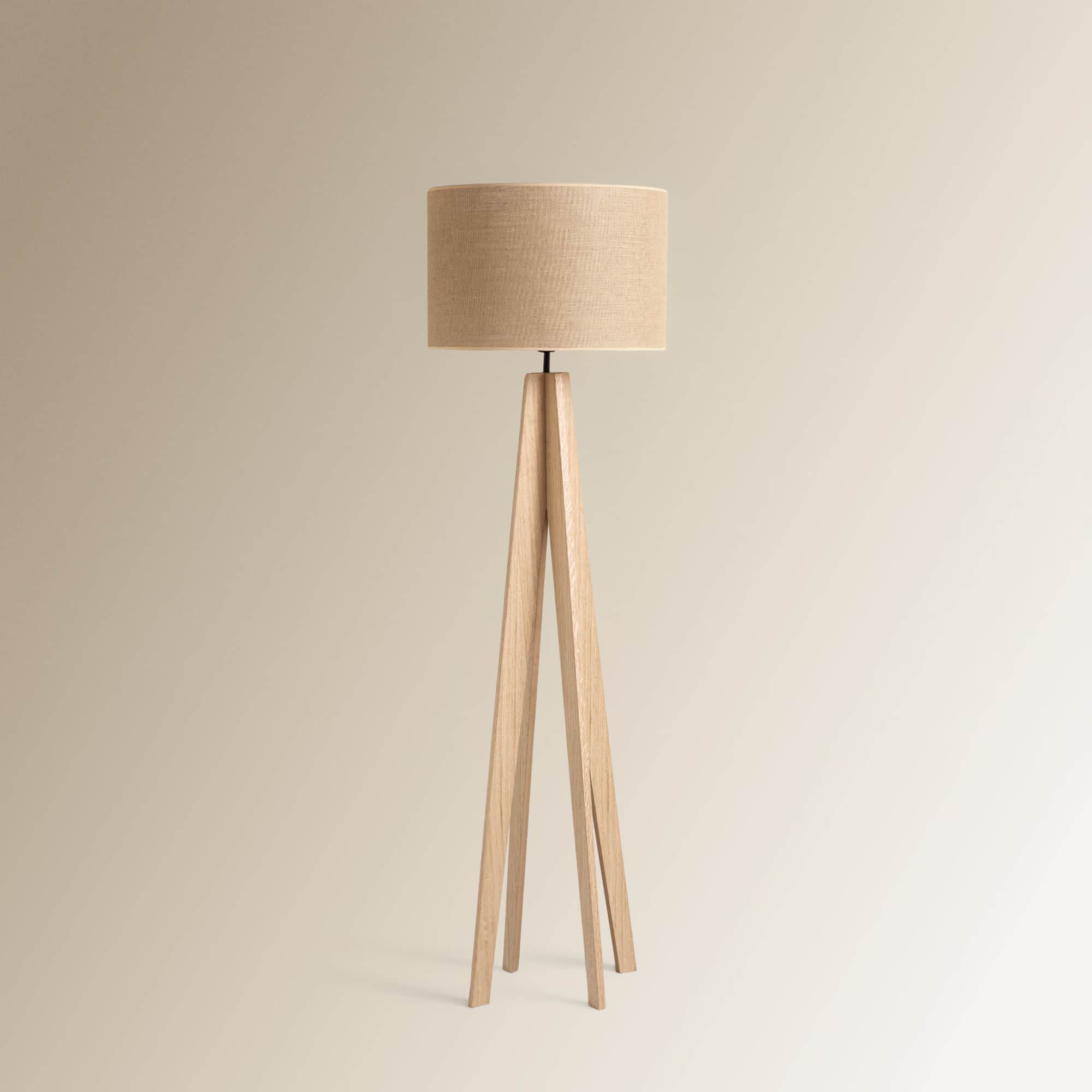 A modern floor lamp featuring a cylindrical, light-colored linen fabric shade atop a splayed, light-… — 3D model