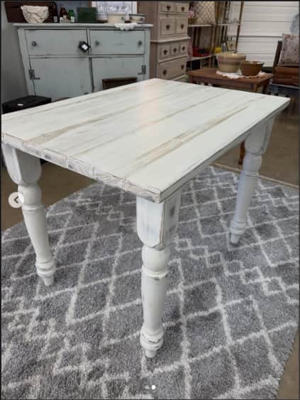 A rectangular, distressed white wooden accent table with four turned legs, presented against a clean… — 3D model