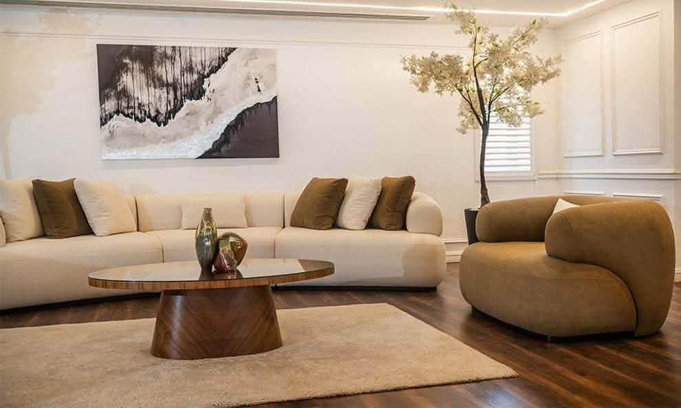 A modular, curved sectional sofa upholstered in a light beige fabric. It features a low profile, rou… — 3D model