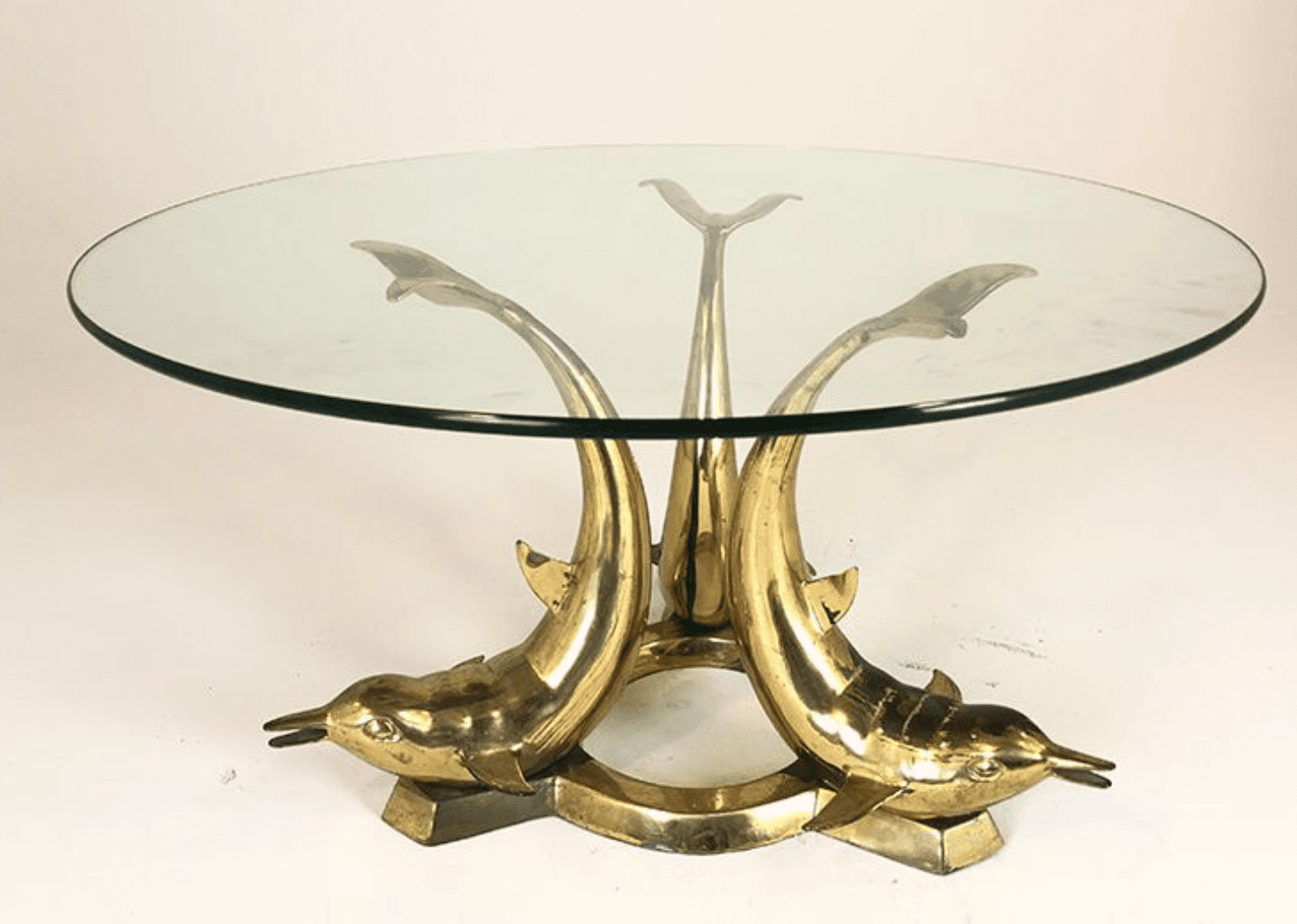 A round glass-top coffee table with a distinctive base. The base is constructed from polished brass… — 3D model