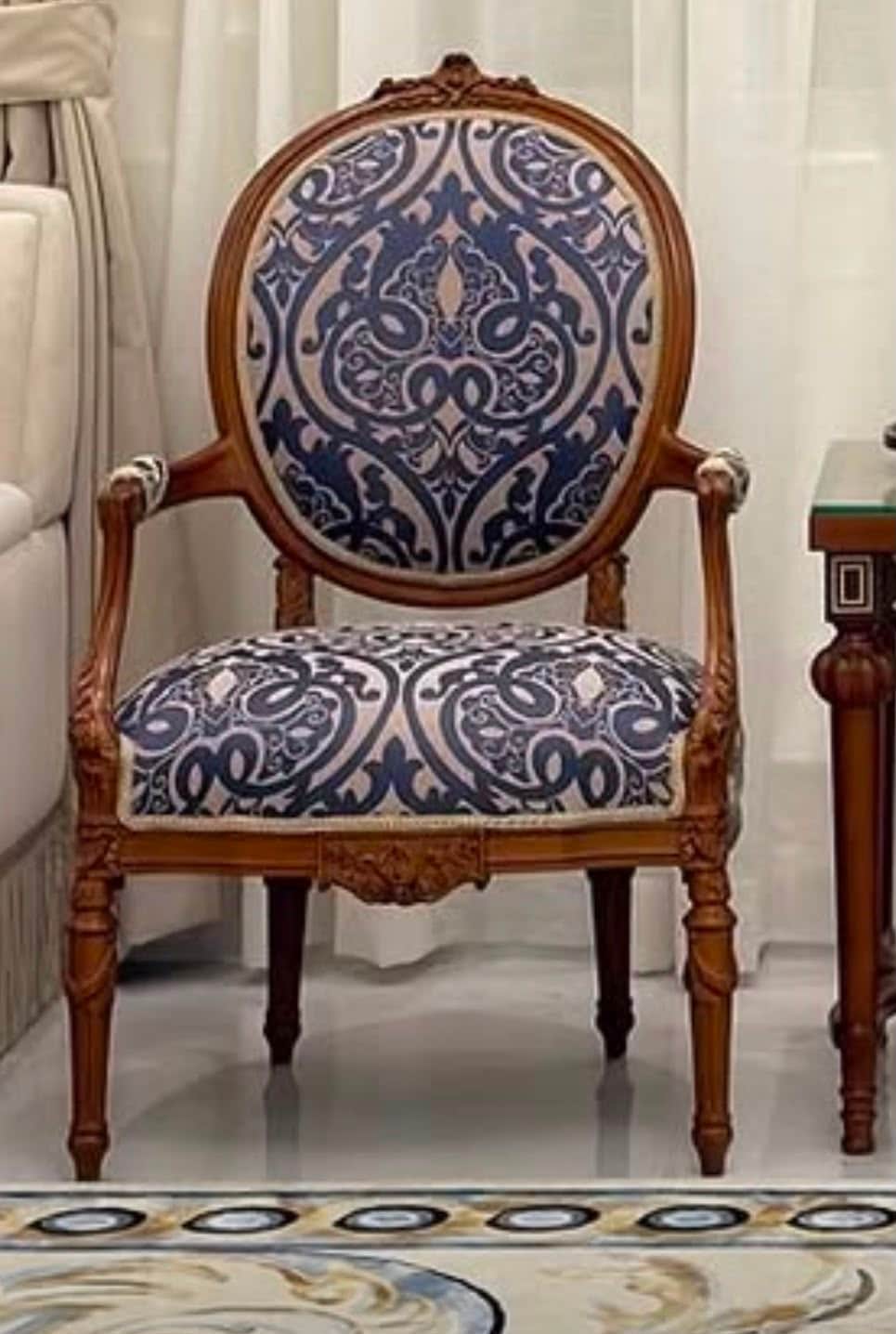 An ornate armchair featuring a carved wooden frame and upholstered in a blue and beige patterned fab… — 3D model