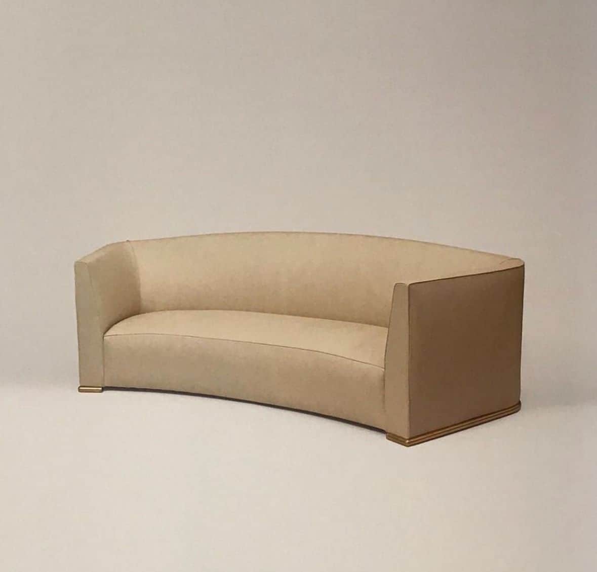 A contemporary curved sofa upholstered in light beige fabric, featuring a continuous back and armres… — free GLTF 3D model