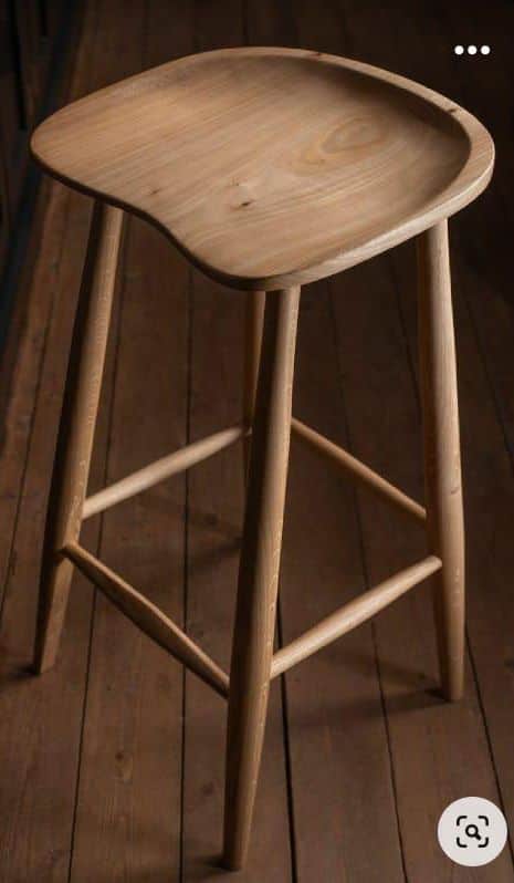 A tall, backless bar stool featuring a sculpted wooden seat and splayed, tapered legs connected by f… — 3D model