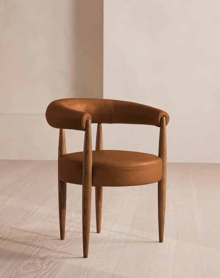 A modern armchair featuring a dark wood frame and saddle leather upholstery. The chair has a curved,… — 3D model