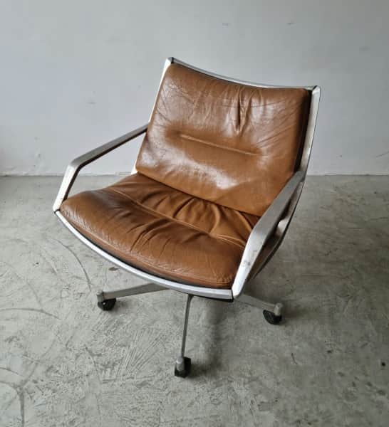 A low-profile armchair with a curved frame and tufted seat and back cushions. The armchair features… — 3D model