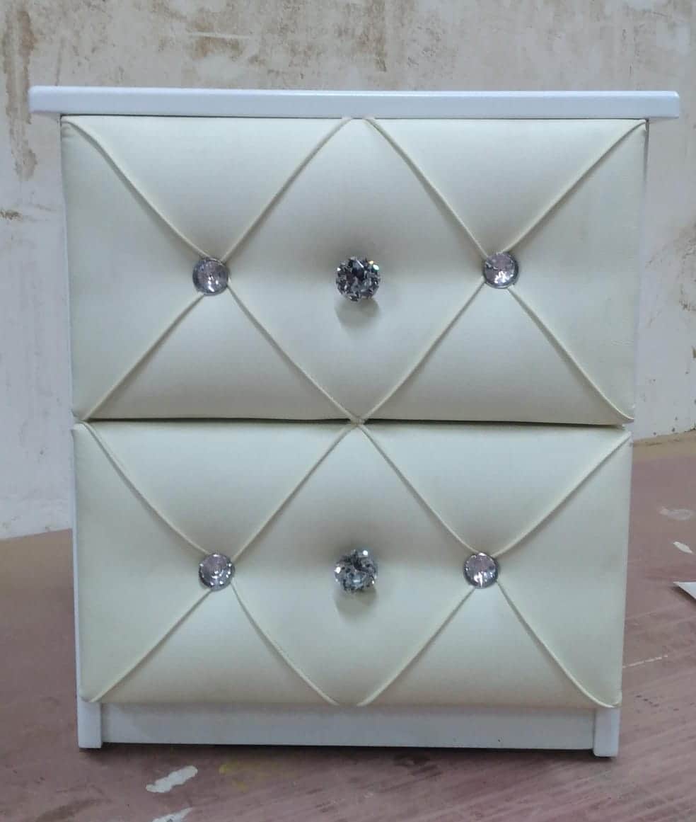 A two-drawer nightstand with a white frame and cream-colored upholstered drawer fronts featuring tuf… — 3D model