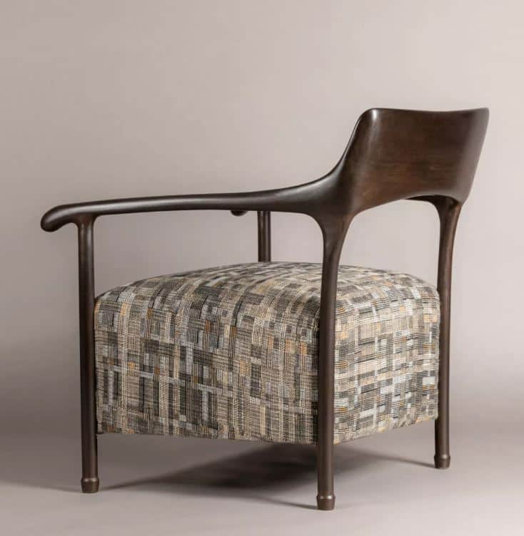 A modern armchair featuring a dark, sculptural wooden frame that forms the armrests, backrest, and l… — 3D model