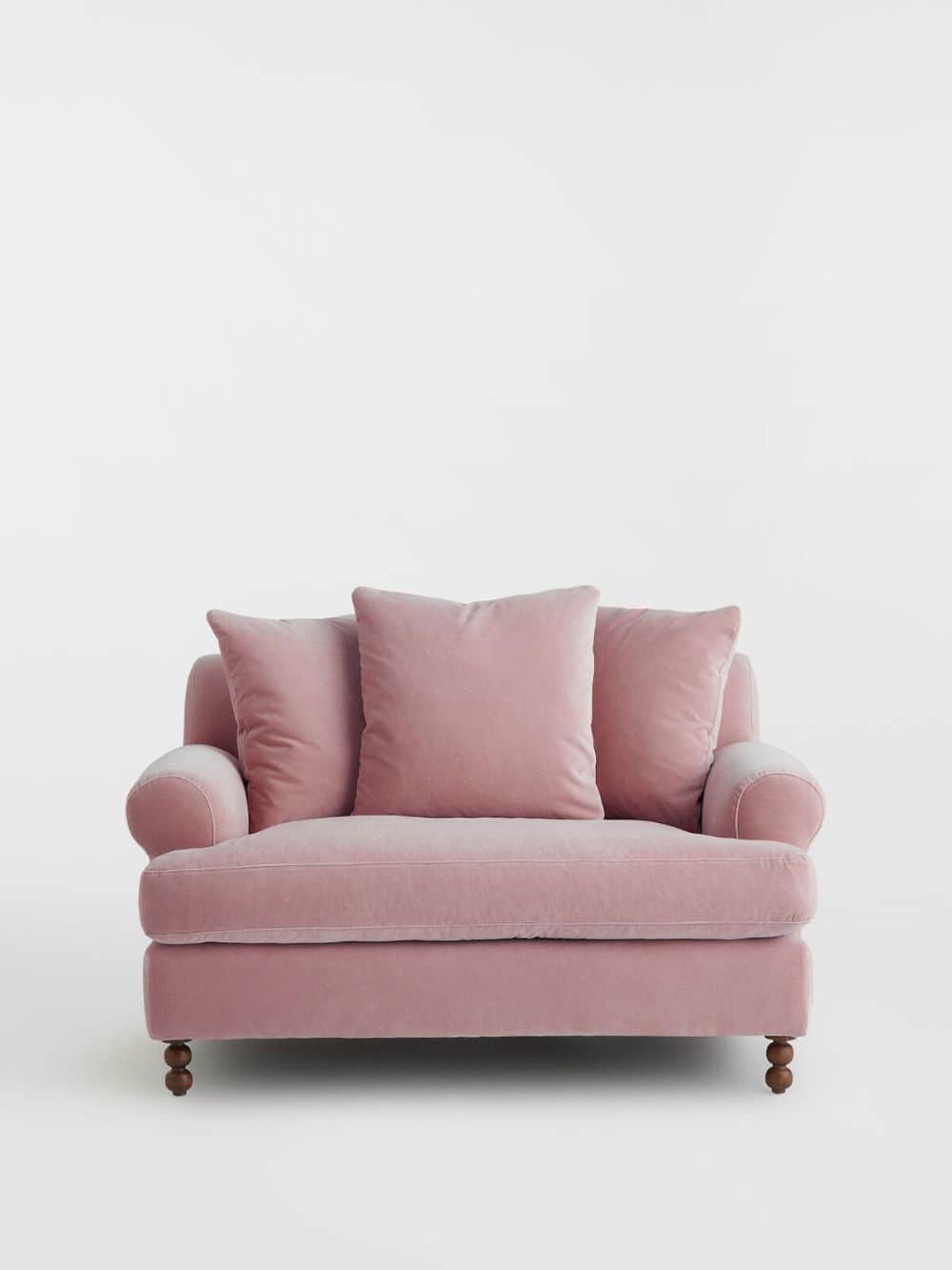 A plush pink sofa with rolled arms, featuring three throw pillows and dark wooden, turned legs. The… — free GLTF 3D model