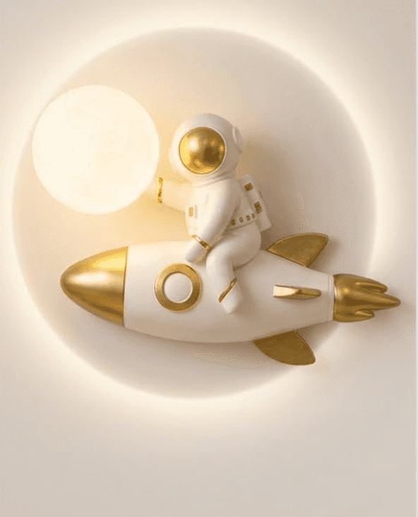 A whimsical wall-mounted lamp featuring a white and gold astronaut figure sitting atop a matching ro… — 3D model