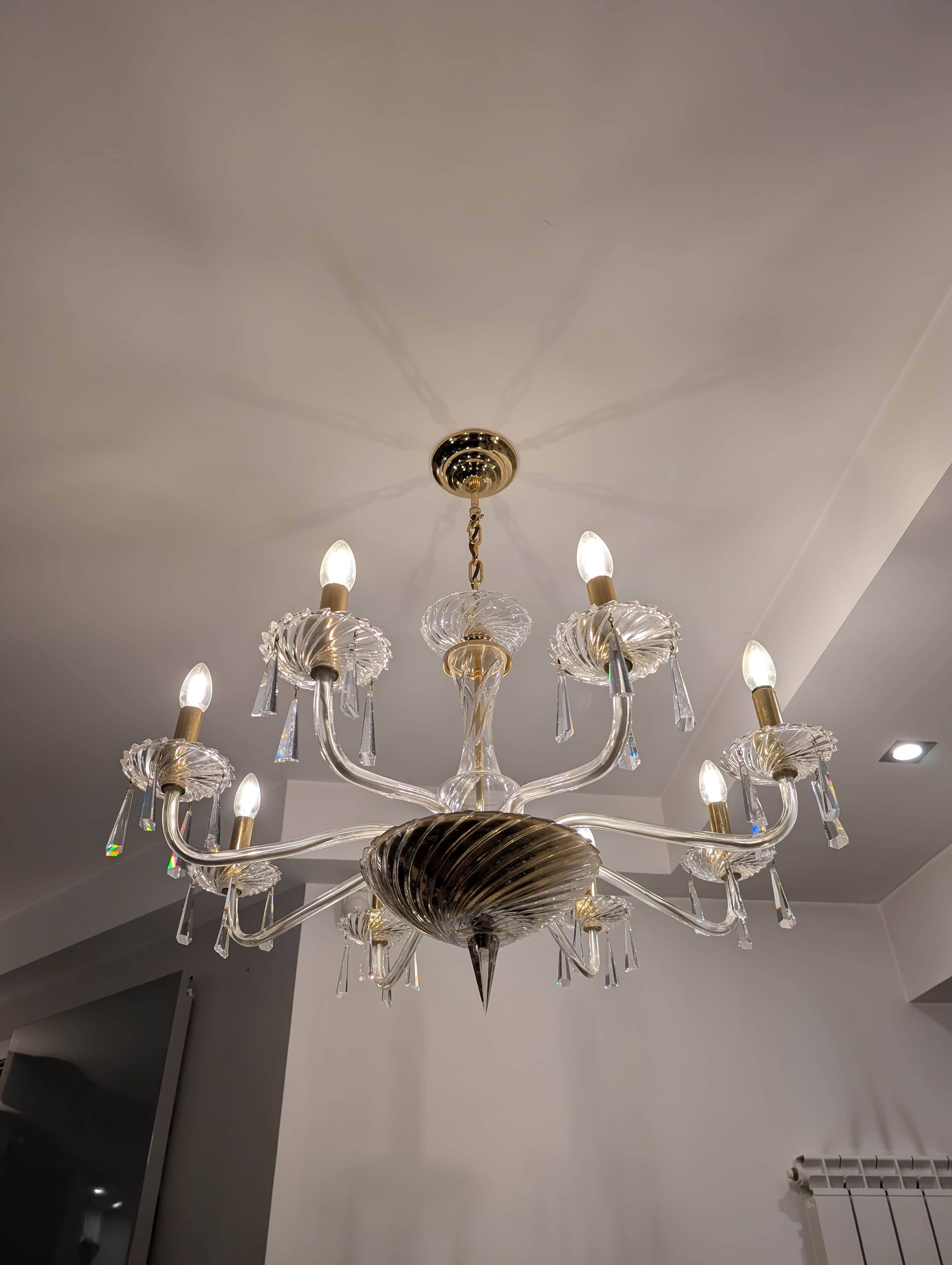 A multi-tiered chandelier with eight arms, featuring clear glass elements and crystal pendants. The… — 3D model