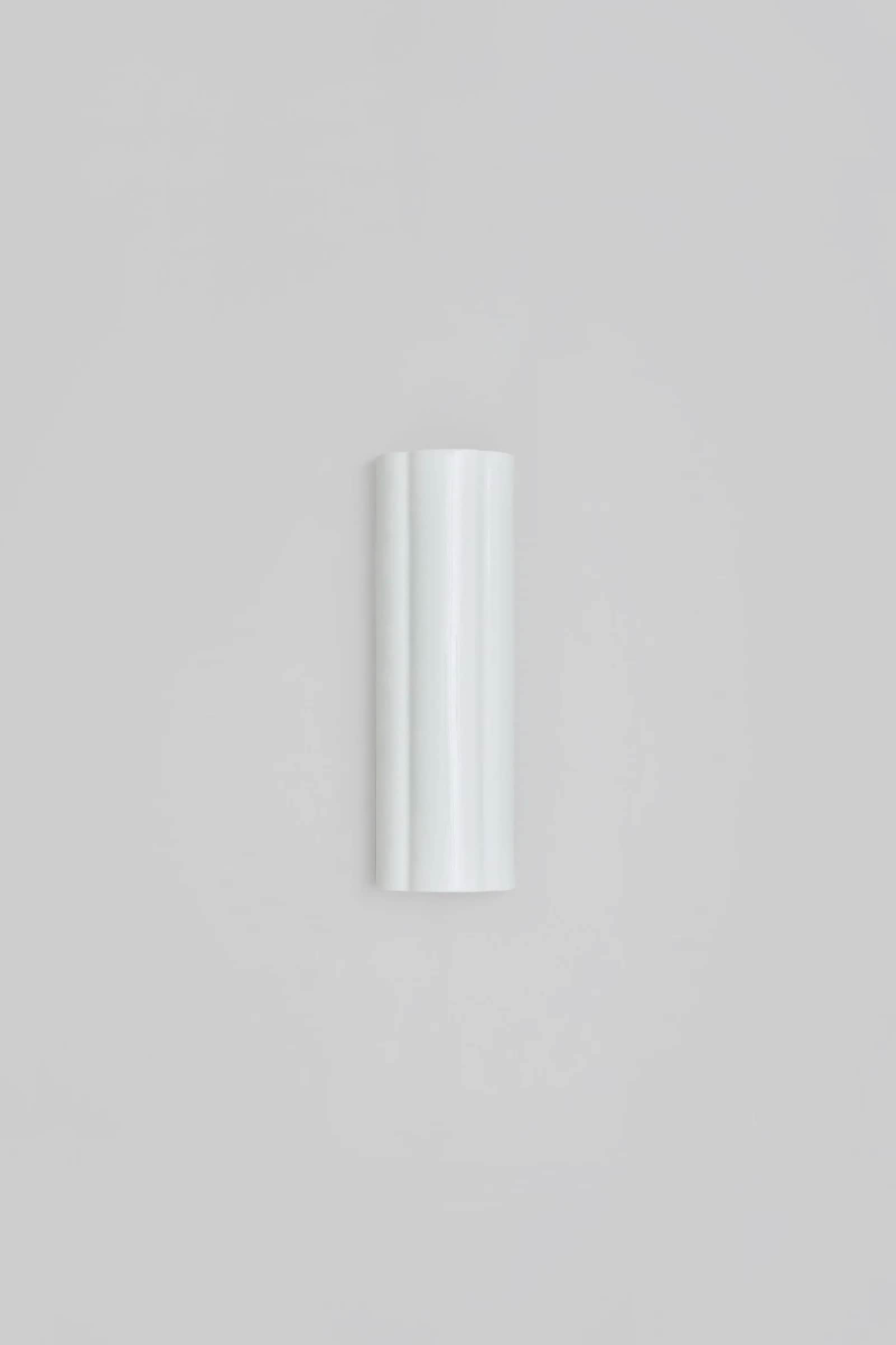 A vertical, cylindrical wall-mounted light fixture featuring a prominent fluted or ribbed design on… — 3D model