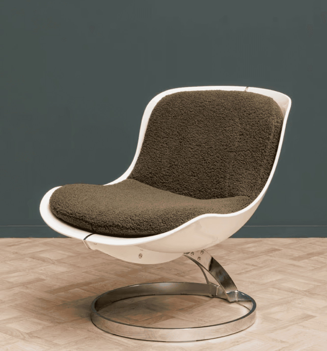 A modern armchair featuring a white molded shell seat and back, with a thick, textured green cushion… — 3D model