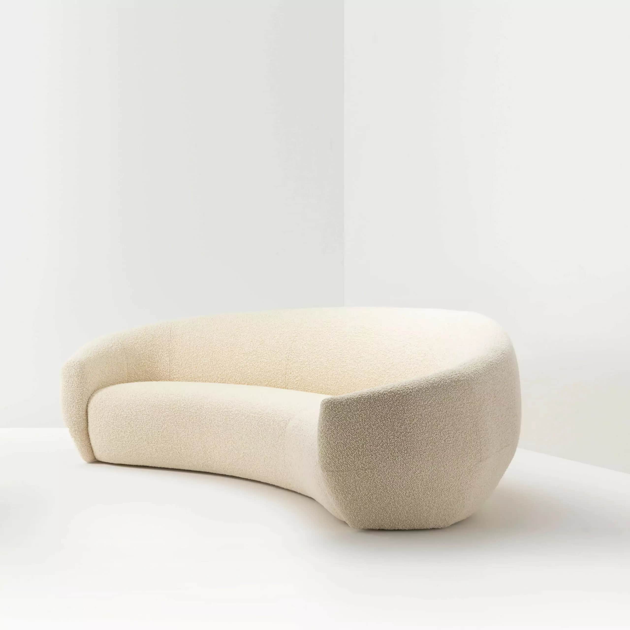 A cream-colored, curved sofa with a textured fabric upholstery. The sofa features a continuous, orga… — 3D model