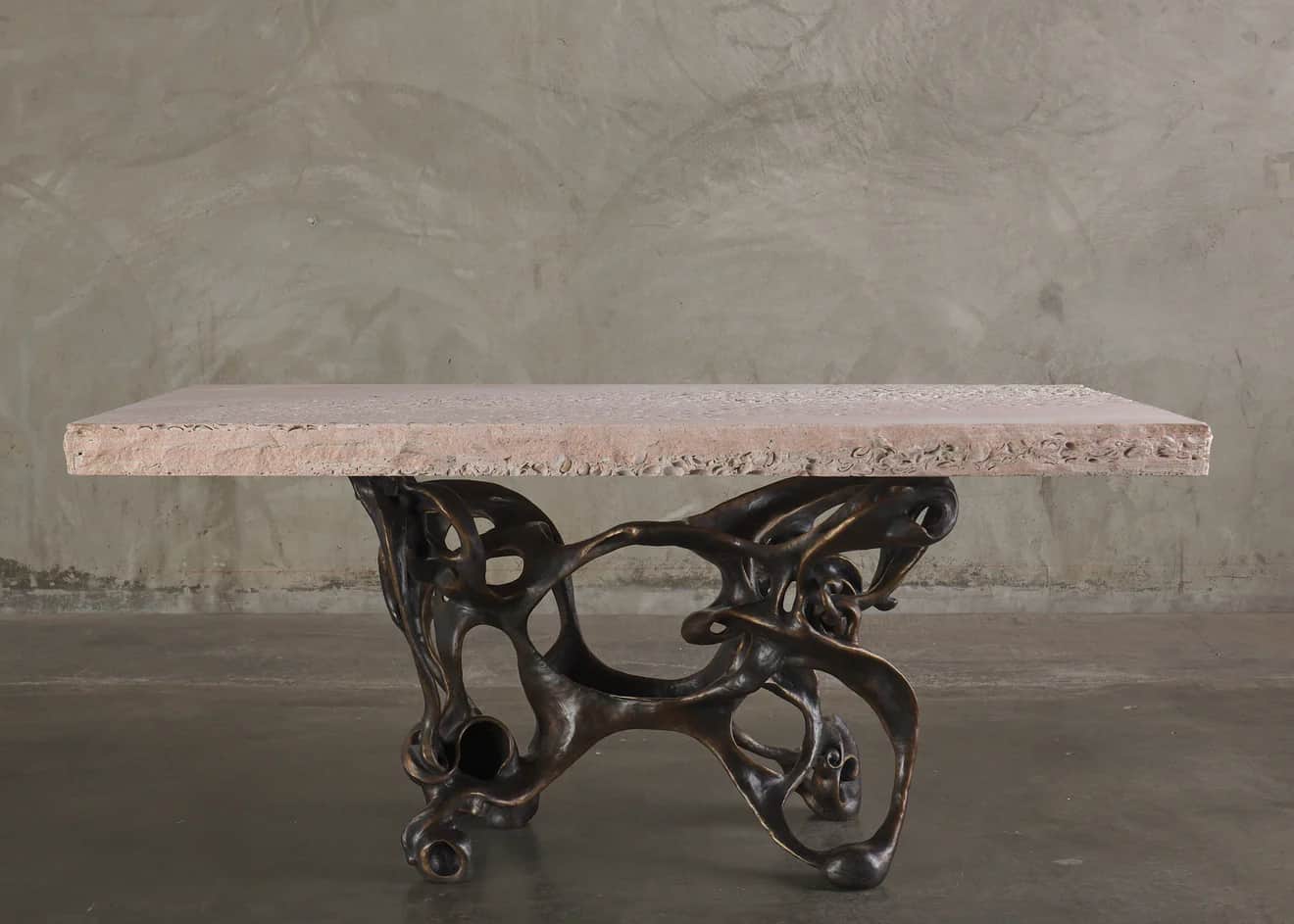 A console table with a rectangular, light pinkish-beige stone top and an intricately sculpted, dark… — 3D model