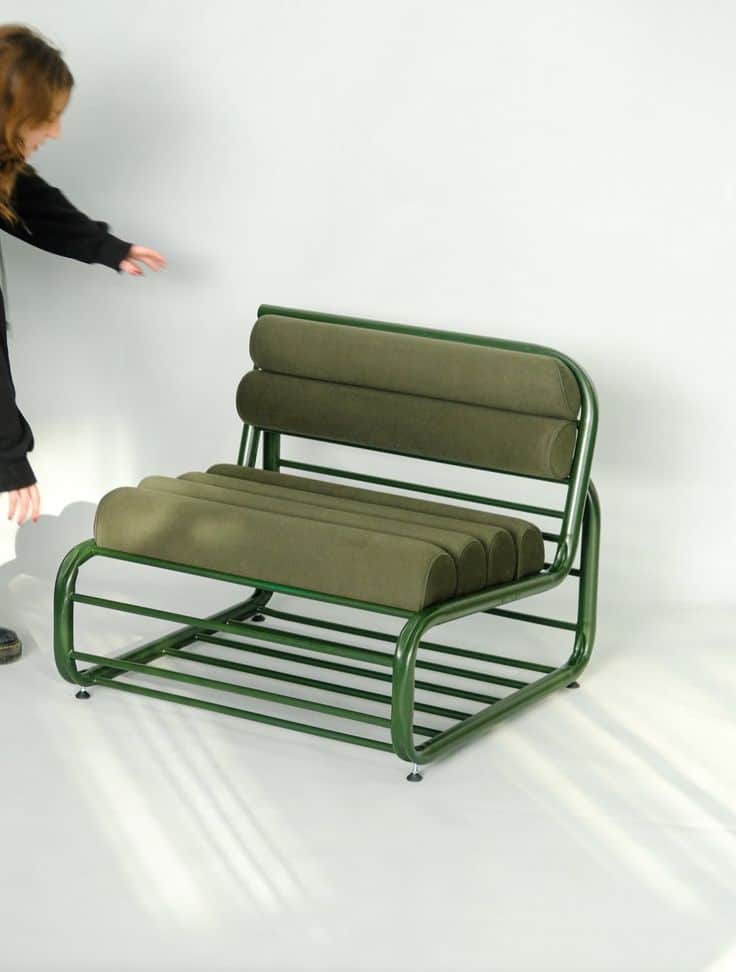 A modern lounge chair featuring a bent tubular steel frame and bolster-style cushions, all finished… — 3D model