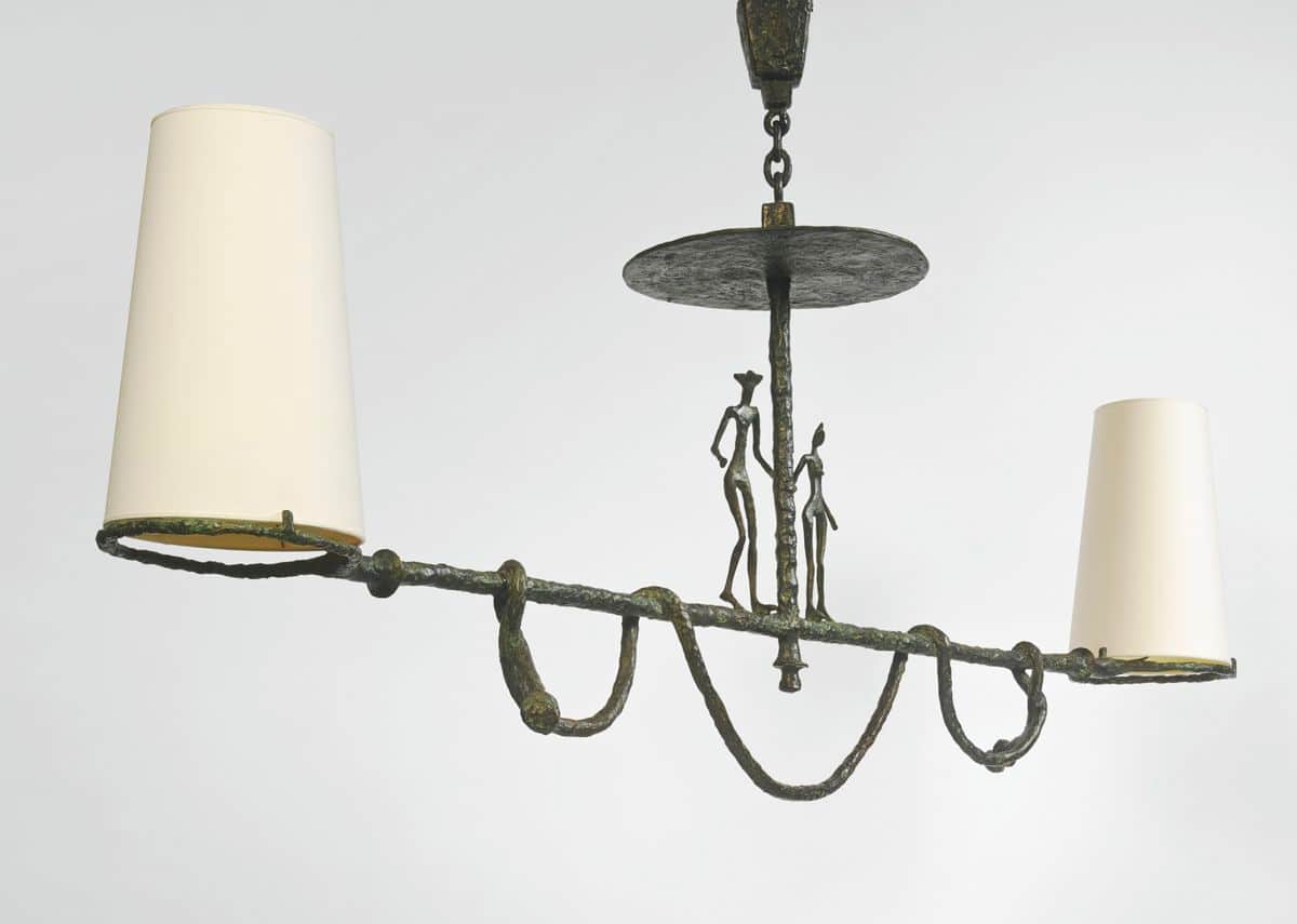 A decorative chandelier with a central stem supporting a flat disc. Two stylized human figures are a… — 3D model