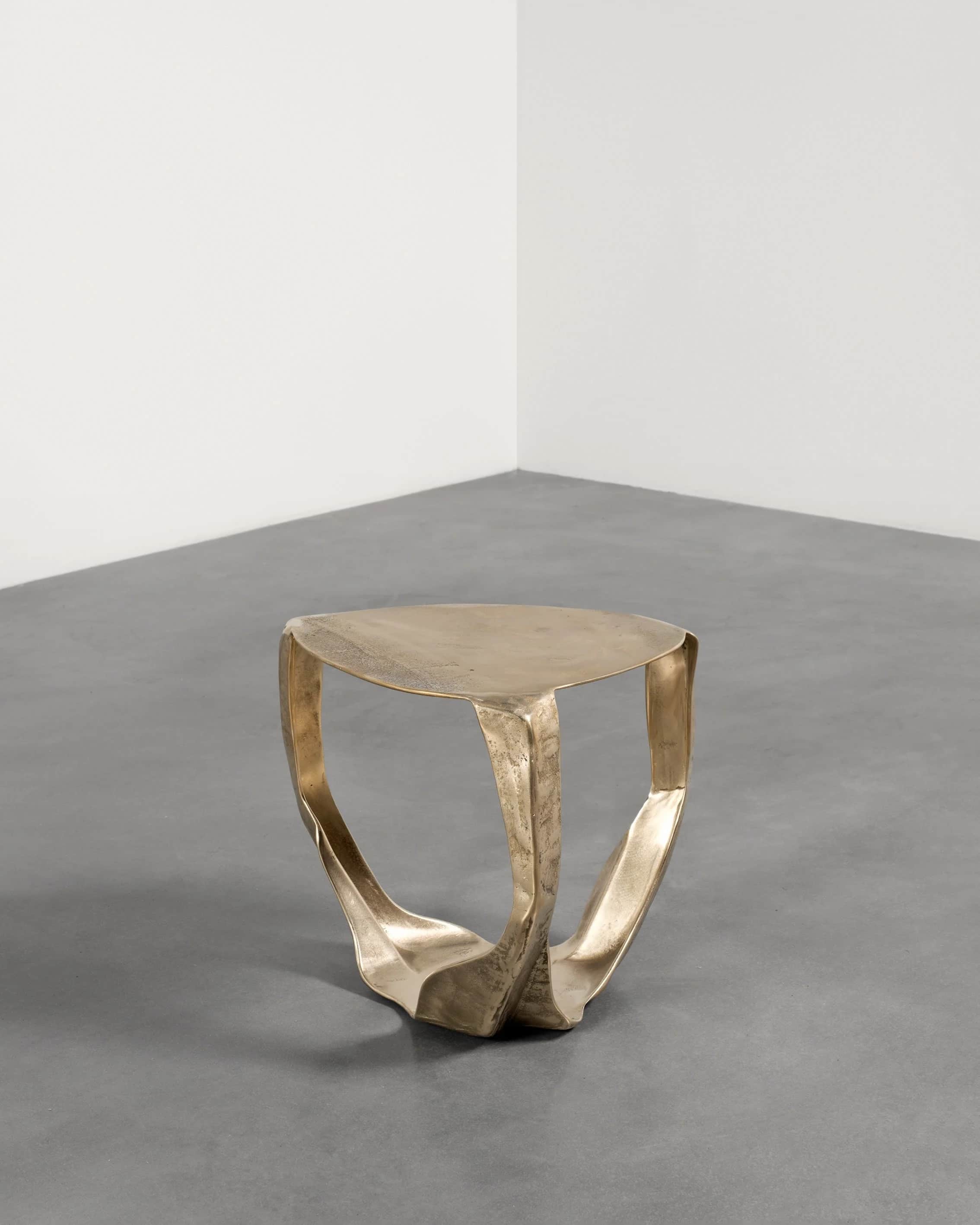 A sculptural accent table crafted from brass with an organic, fluid form. The table features a round… — 3D model