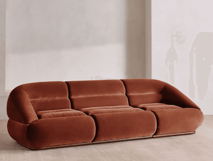 A contemporary three-seater sofa characterized by its rounded, curvilinear form and plush terracotta… — free GLTF 3D model