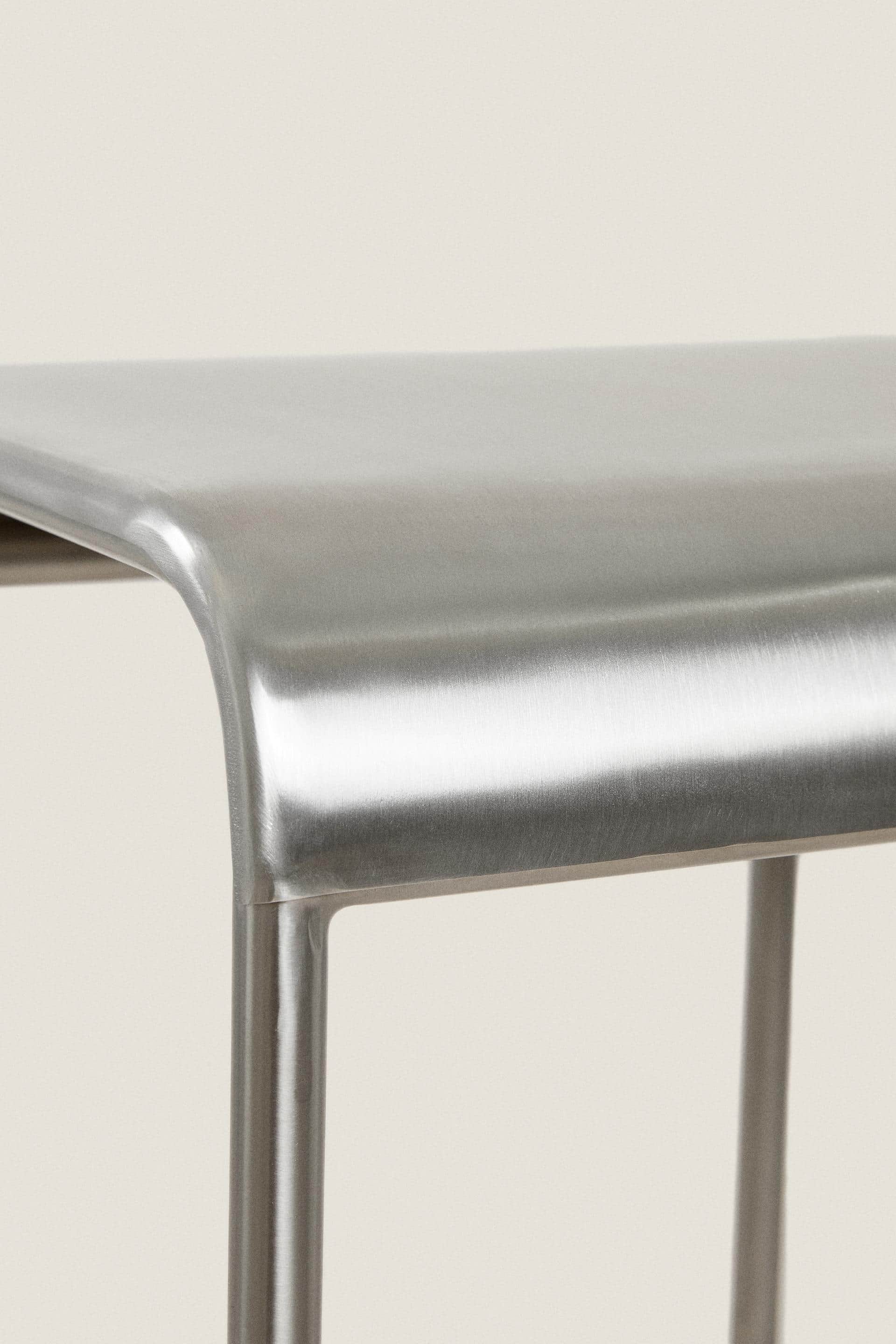 A close-up image displaying the upper portion of a backless stool crafted from brushed metal. The se… — 3D model