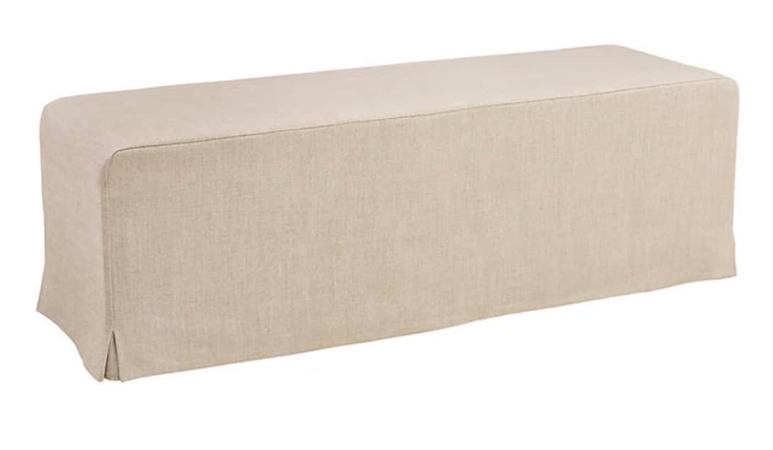 A rectangular, upholstered bench featuring a full-length, light-colored fabric slipcover that extend… — 3D model