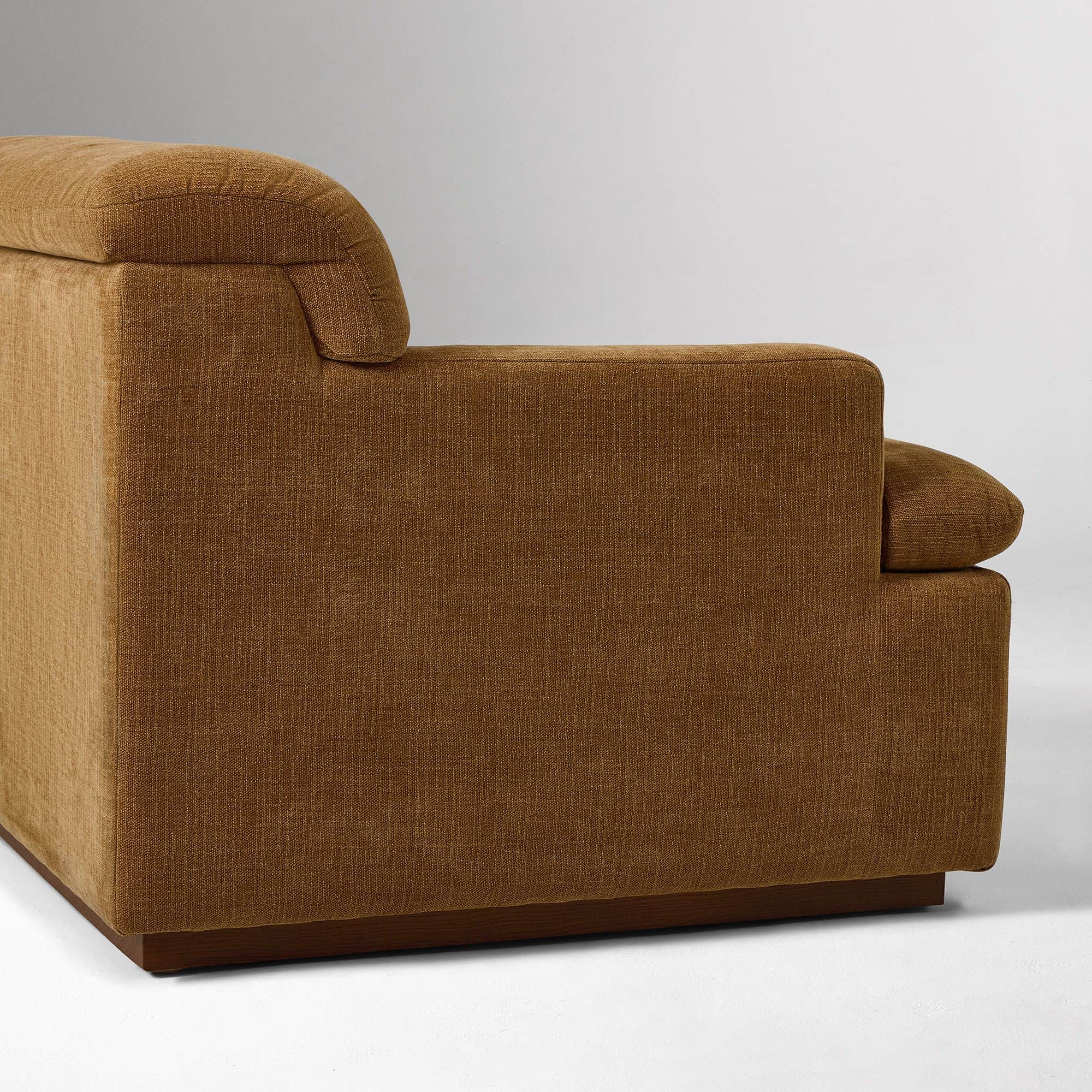 A close-up view of the armrest and side of a sofa. The sofa is upholstered in a textured, woven fabr… — 3D model