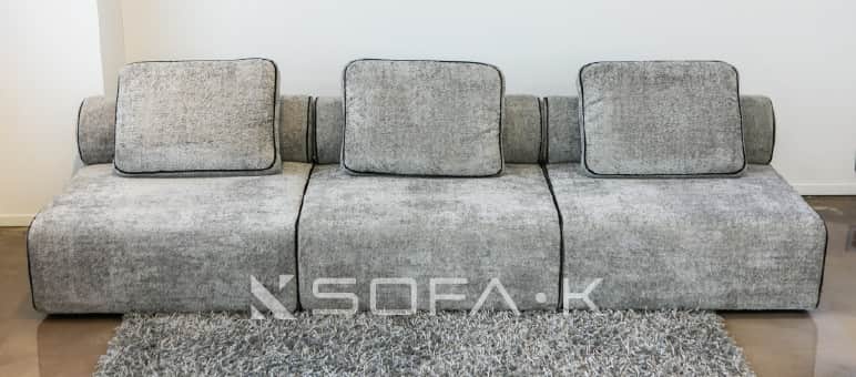 A contemporary, low-profile modular sofa upholstered in a textured, speckled grey fabric. The sofa c… — free GLTF 3D model