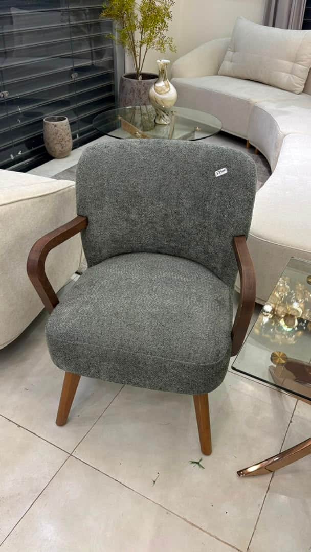 A contemporary upholstered armchair featuring a rounded backrest and seat, gray textured fabric, and… — 3D model