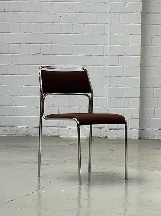 An armless side chair featuring a polished chrome tubular metal frame with a dark brown upholstered… — 3D model