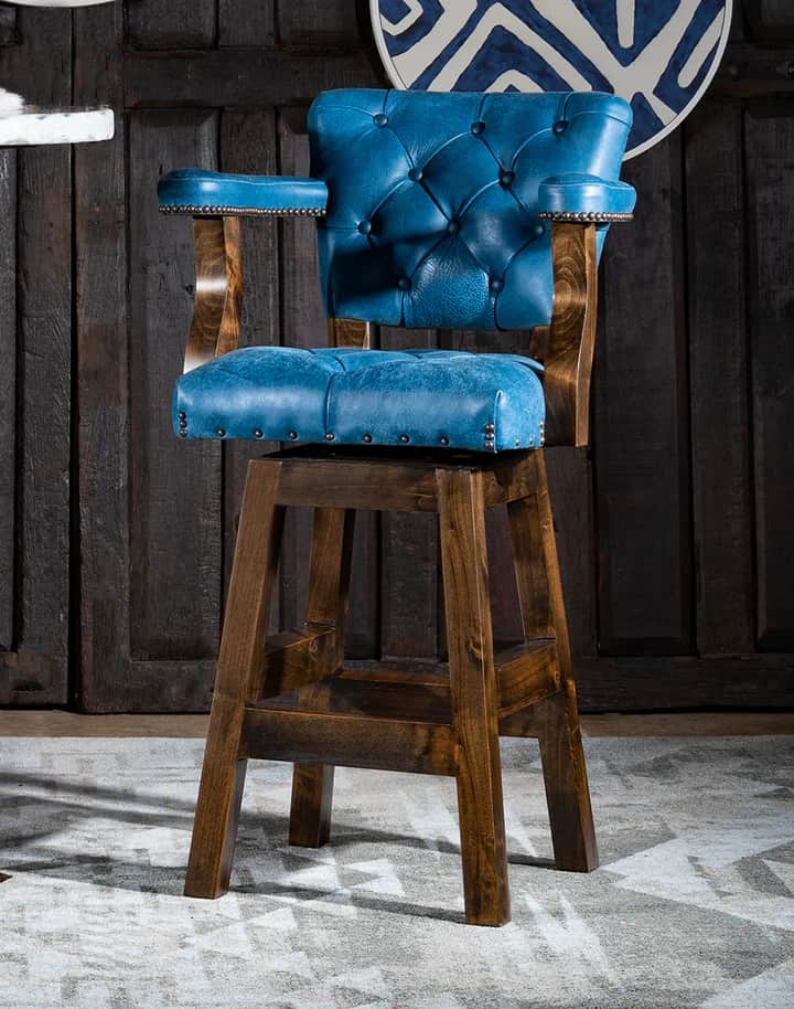 A traditional-style bar stool featuring a tufted, blue upholstered seat and back with armrests, supp… — 3D model
