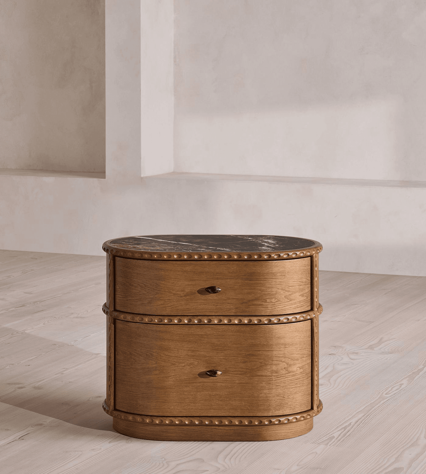 A small, oval-shaped wooden nightstand featuring two drawers and a black marble top with white veini… — 3D model