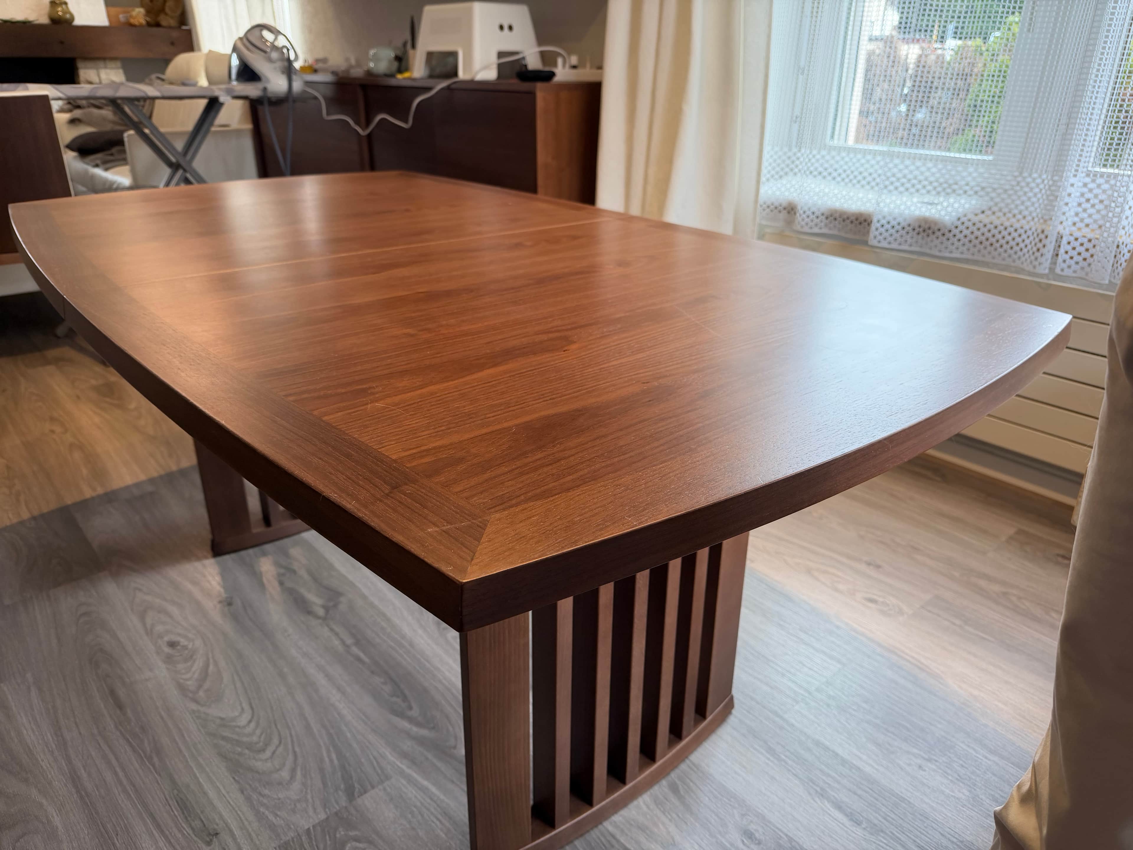 A modern dining table featuring a dark brown wooden top with elegantly curved edges and a matching s… — 3D model