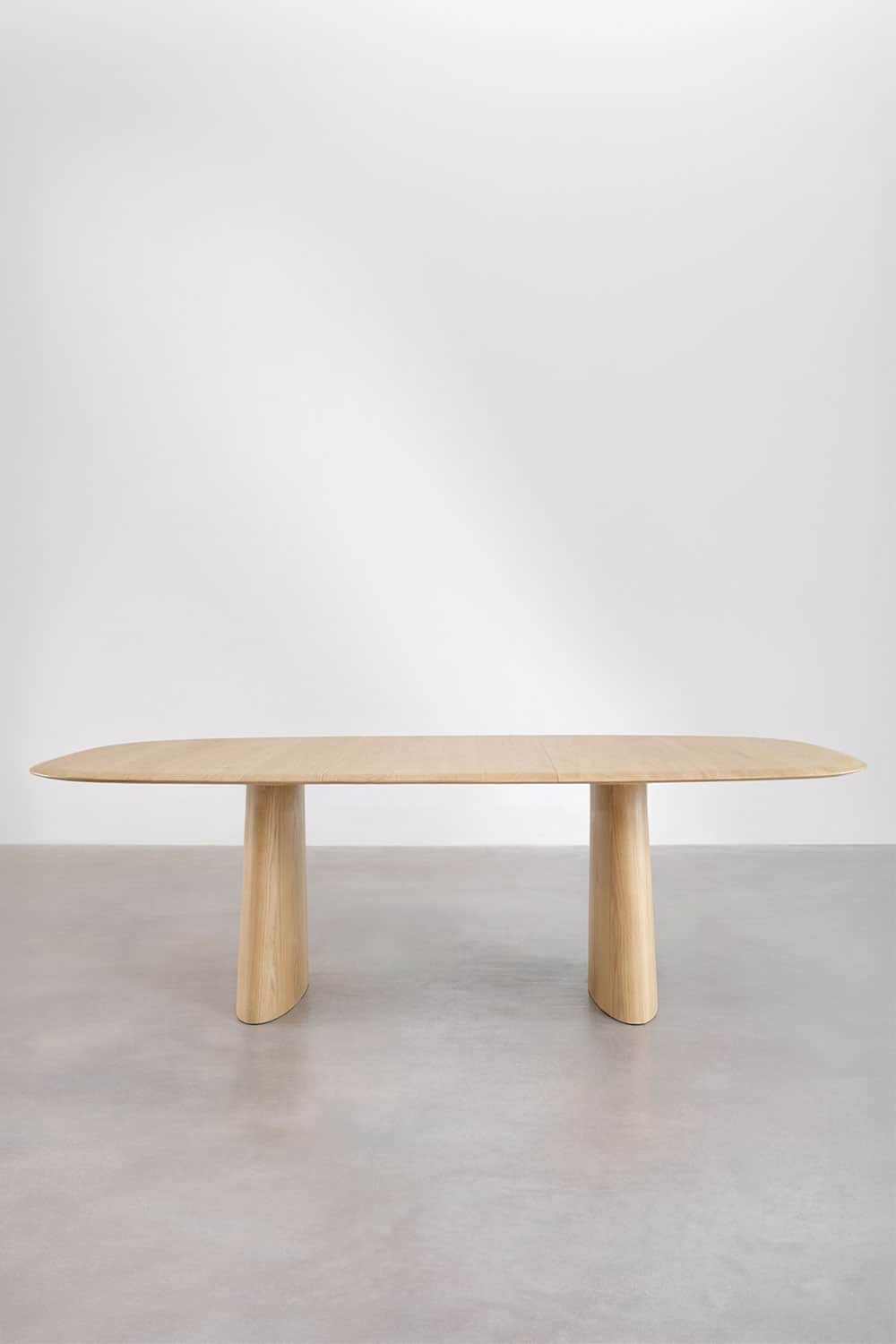 A minimalist dining table featuring an elongated oval tabletop crafted from light-toned wood, likely… — 3D model