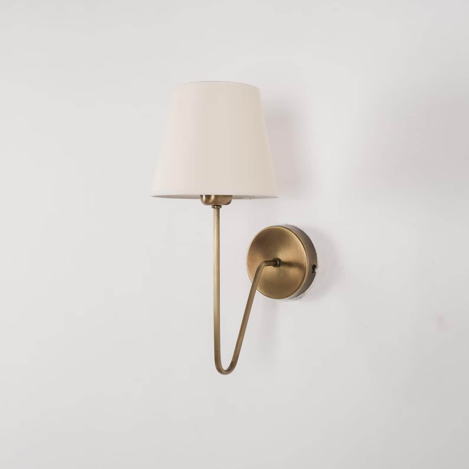 A wall-mounted lamp with a conical, cream-colored fabric shade and a brass-finished metal arm and ba… — 3D model