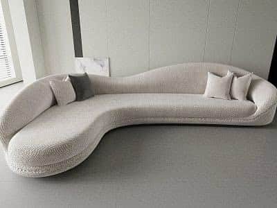 An off-white, serpentine-shaped sofa upholstered in a boucle fabric, featuring a continuous, undulat… — free GLTF 3D model