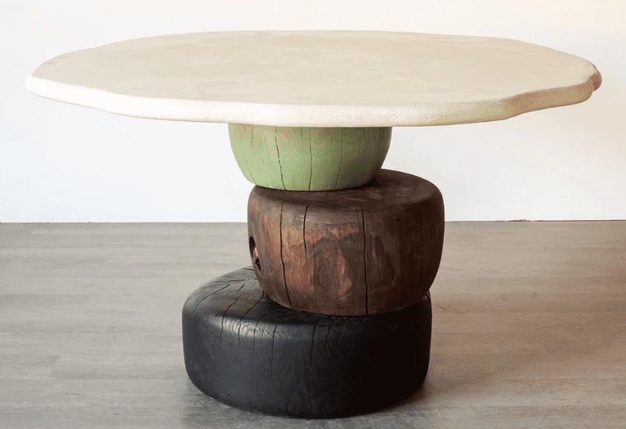 An accent table featuring an irregularly shaped, off-white plaster or concrete top, supported by a s… — 3D model