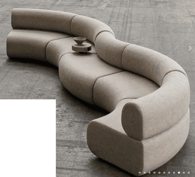 A modular, serpentine-shaped sofa with a low profile. The sofa is upholstered in a textured, light-c… — 3D model