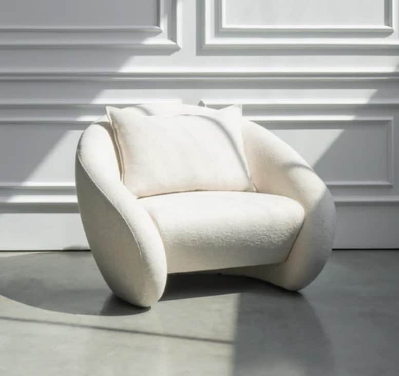 A contemporary lounge chair with a rounded, organic silhouette, fully upholstered in a textured, off… — 3D model